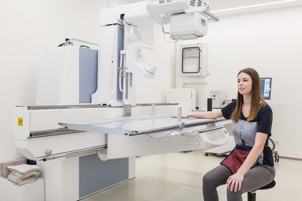 Das Digitale Röntgengerät in der Ordination. Davor sitzteine Dame.