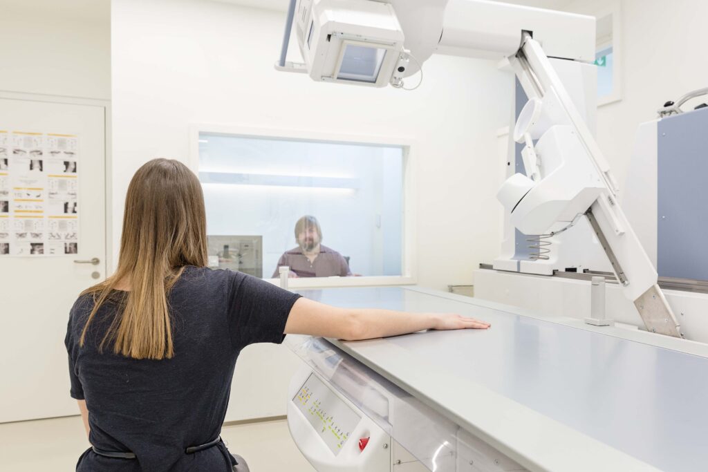 Eine Patientin hat den Unterarm auf das digitale Röntgengerät gelegt.